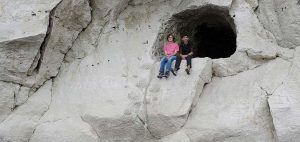 Engineering in London- two students sit on a rock outside a cave entrance
