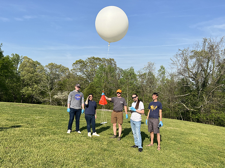 Two student members of the UT Amateur Radio Club, along with three students from Roane State Community College, prepare a radio balloon for launch in a grassy field