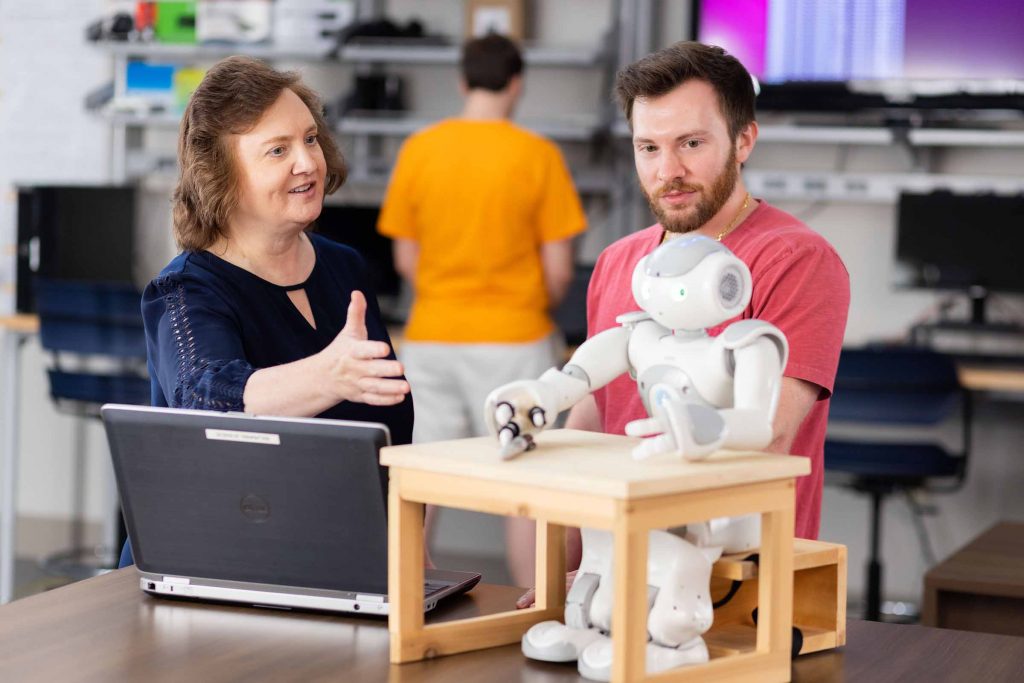 Lynne Parker looks at a robot in a lab with a student