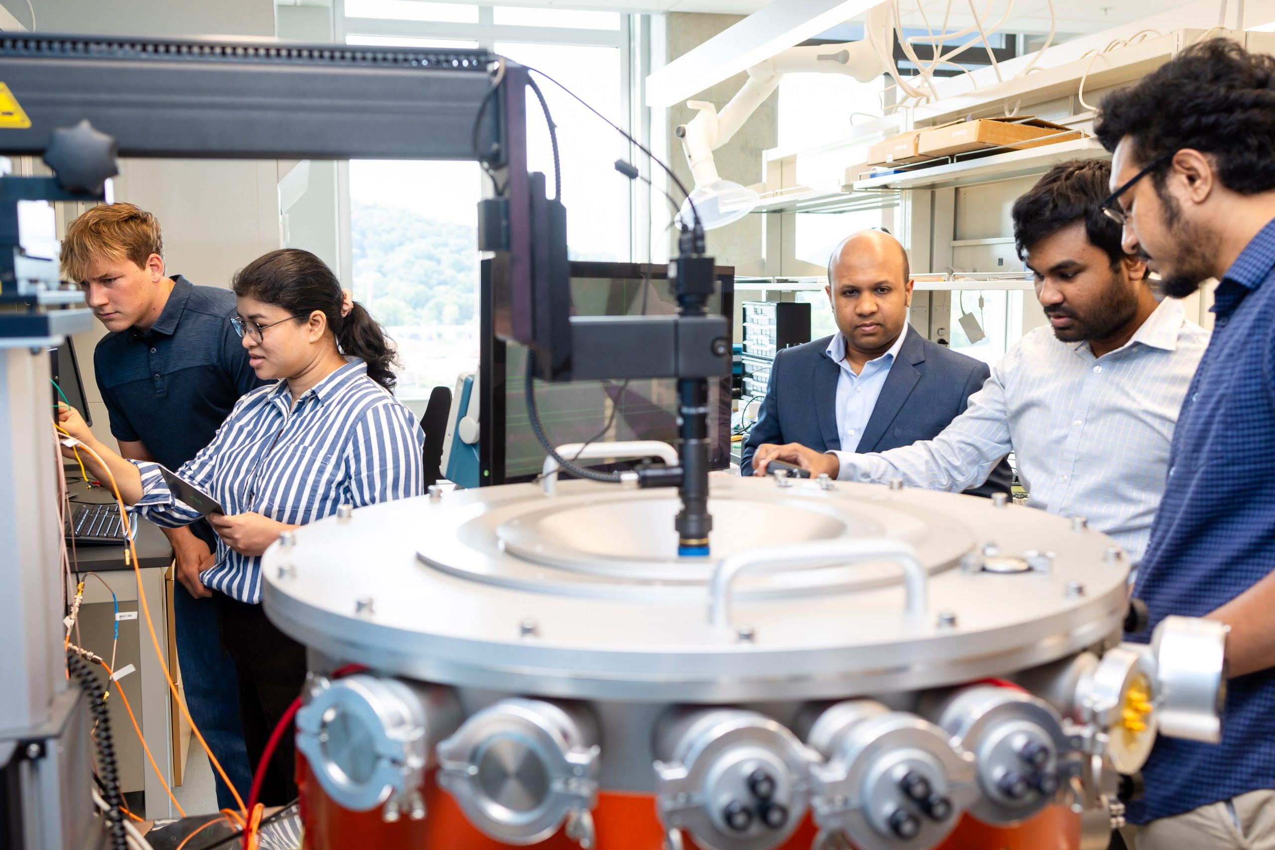 Ahmendullah Aziz guiding students in a lab to use a machine